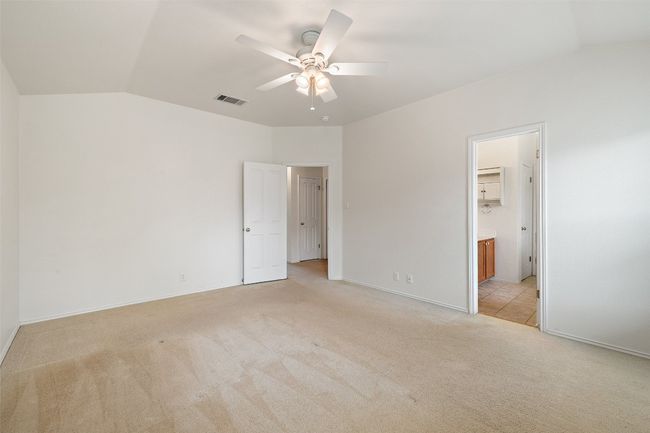 Unfurnished bedroom featuring visible vents, light carpet, ensuite bathroom, and lofted ceiling | Image 25