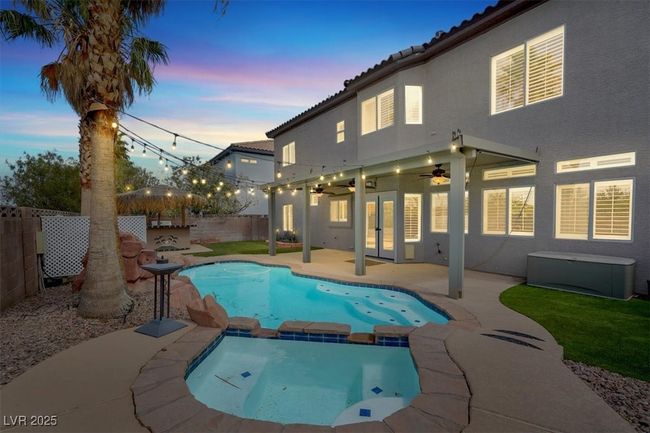Pool at dusk with a fenced backyard, a pool with connected hot tub, ceiling fan, a patio, and french doors | Image 38