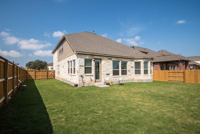 Rear view of property featuring a lawn, roof with shingles, a fenced backyard, and stone siding | Image 26