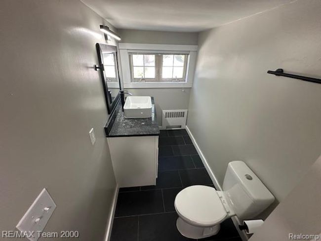 Bathroom with vanity, dark tile patterned flooring, and radiator | Image 25
