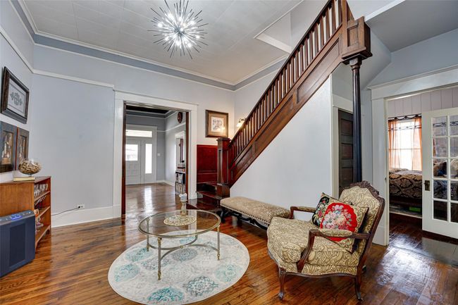 Foyer entrance with stairway, wood-type flooring, crown molding, baseboards, and a chandelier | Image 5