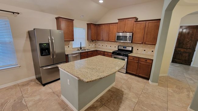 Kitchen with appliances with stainless steel finishes, arched walkways, decorative backsplash, a kitchen island, and lofted ceiling | Image 7