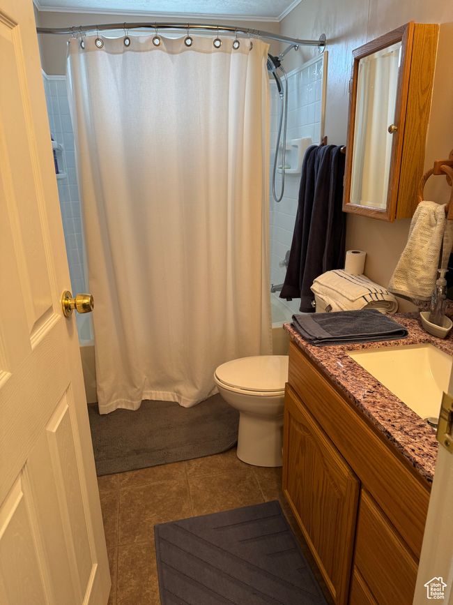 Full bathroom with shower / bath combo, vanity, tile patterned floors, toilet, and crown molding | Image 16