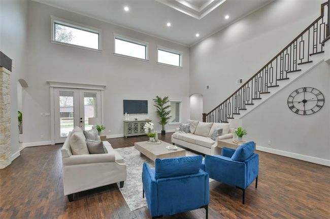 This spacious living room features a bright, airy atmosphere with high vaulted ceilings and large windows that flood the space with natural light. The open layout seamlessly connects to the adjacent kitchen, enhancing the sense of flow and spaciousness in this beautiful living area. | Image 11