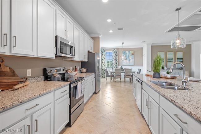 Kitchen with hanging light fixtures, a sink, white cabinets, and stainless steel appliances | Image 18