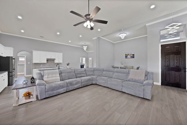 Living area with ceiling fan, arched walkways, ornamental molding, lofted ceiling, and baseboards | Image 14