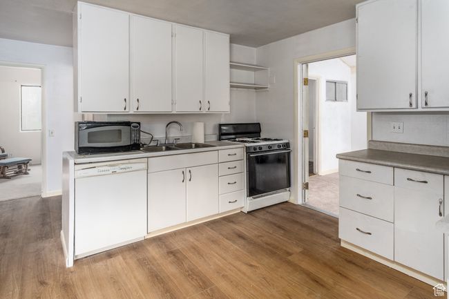 Kitchen featuring white dishwasher, gas range, black microwave, wood finished floors, and white cabinets | Image 18