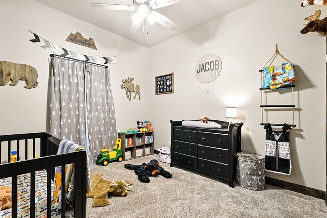 Carpeted bedroom with lofted ceiling, a nursery area, and a ceiling fan | Image 25