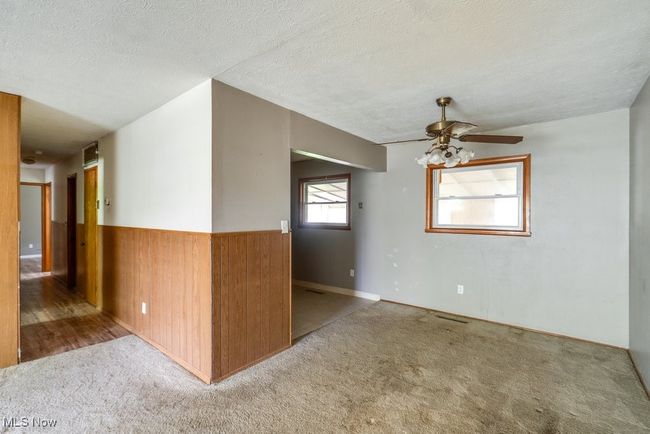 Spare room with carpet flooring, ceiling fan, a wainscoted wall, a textured ceiling, and wooden walls | Image 12