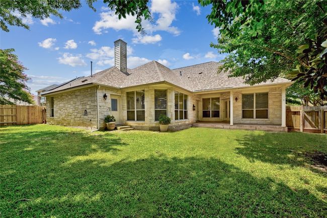 Back of house with stone siding, a chimney, a fenced backyard, and a shingled roof | Image 29