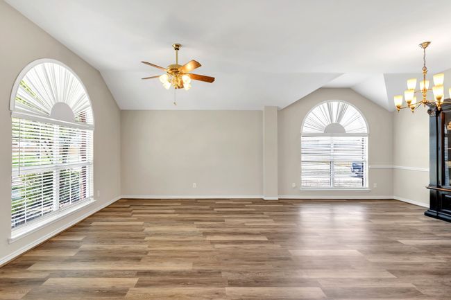 Large Living area featuring lofted ceiling, baseboards, Luxury Vinyl floors, and ceiling fan plus lovely chandelier | Image 5