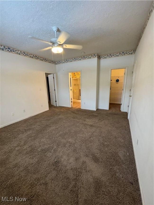 Empty room featuring ceiling fan, a textured ceiling, and dark colored carpet | Image 14
