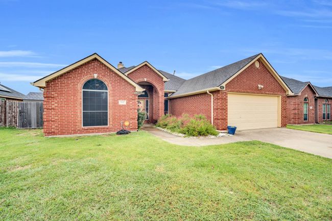 View of front facade featuring brick siding, a garage, driveway, a chimney, and roof with shingles | Image 38