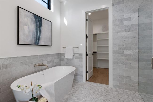 Full bathroom with tile walls, a freestanding tub, a spacious closet, wainscoting, and a tile shower | Image 11