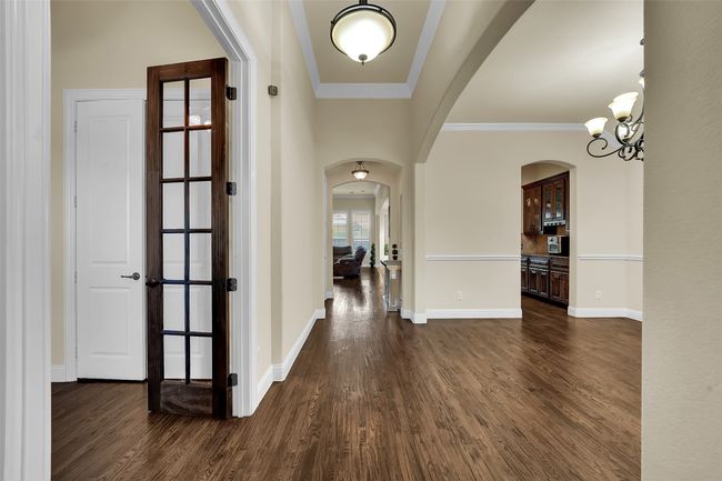 Foyer entrance featuring arched walkways, ornamental molding, dark wood-type flooring, and a chandelier | Image 28
