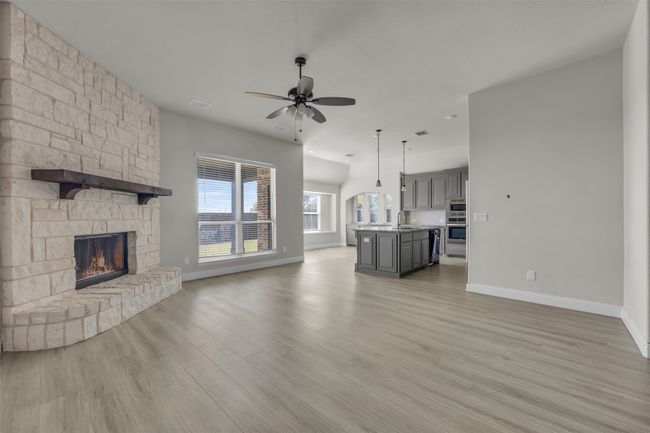 Living room with light wood-type flooring, a stone fireplace and ceiling fan | Image 14