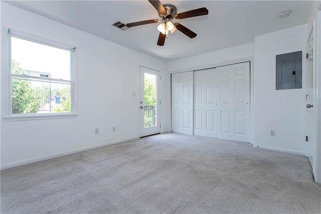 Unfurnished bedroom with electric panel, carpet flooring, a ceiling fan, a closet, and access to exterior | Image 11