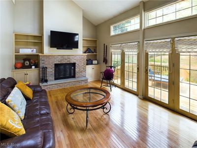 Living room with high vaulted ceiling, a fireplace, light wood-type flooring, and french doors | Image 3