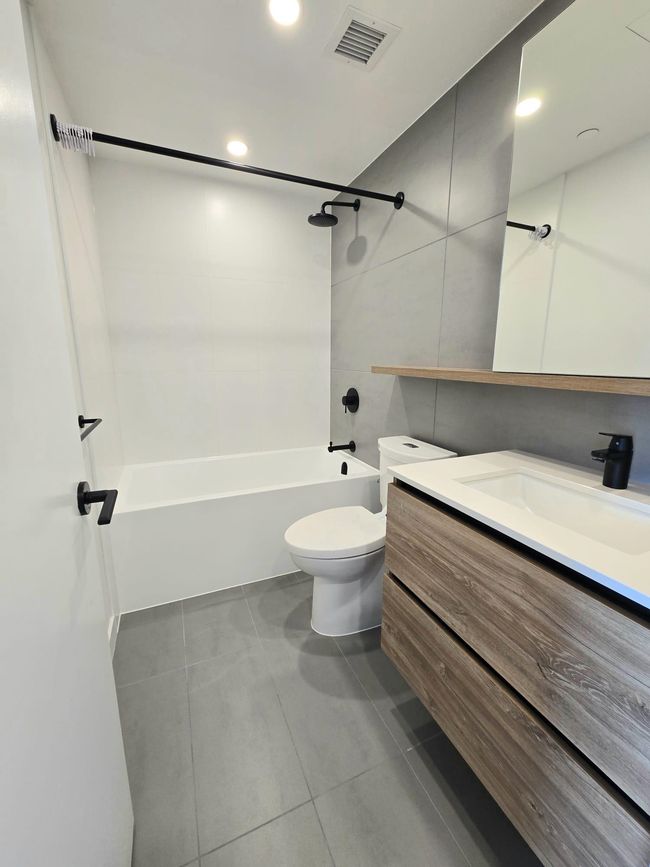 Bathroom with tile patterned floors, visible vents, toilet, vanity, and shower / bathing tub combination | Image 16