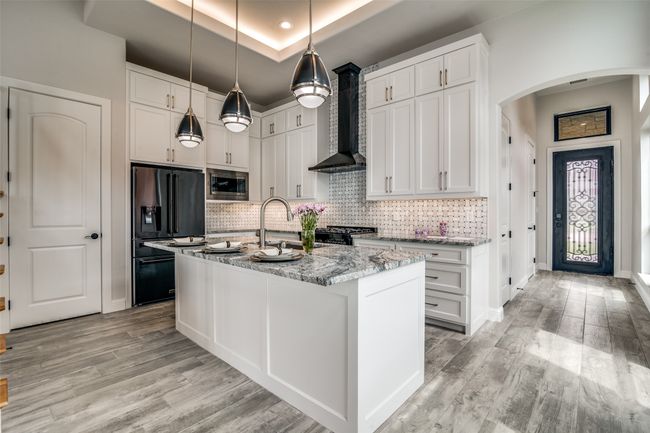 Kitchen featuring light hardwood / wood-style floors, high quality fridge, stainless steel microwave, wall chimney exhaust hood, and a raised ceiling | Image 8