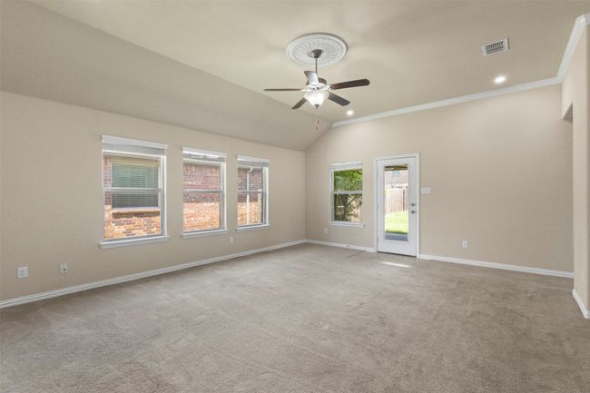Carpeted living room featuring a ceiling fan, crown molding, lofted ceiling, and recessed lighting | Image 13