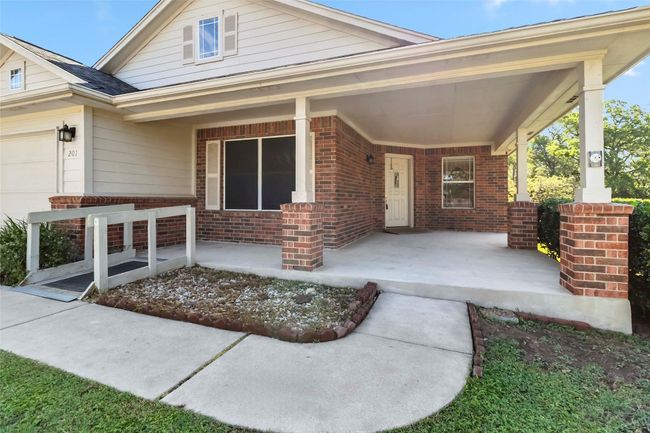 View of front of property with covered porch, brick siding, and an attached garage | Image 4