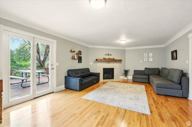 Living area with light wood-style floors, crown molding, and a tile fireplace | Image 44