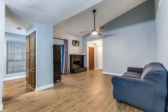 Living area featuring vaulted ceiling, light wood-style floors, a brick fireplace, and a ceiling fan | Image 6