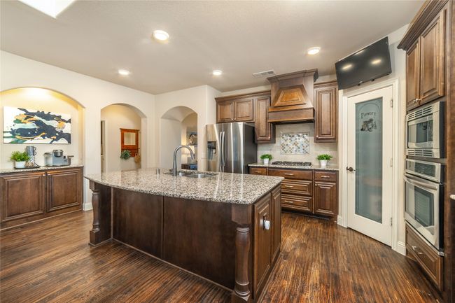Kitchen featuring appliances with stainless steel finishes, custom range hood, a sink, dark wood finished floors, and recessed lighting | Image 10