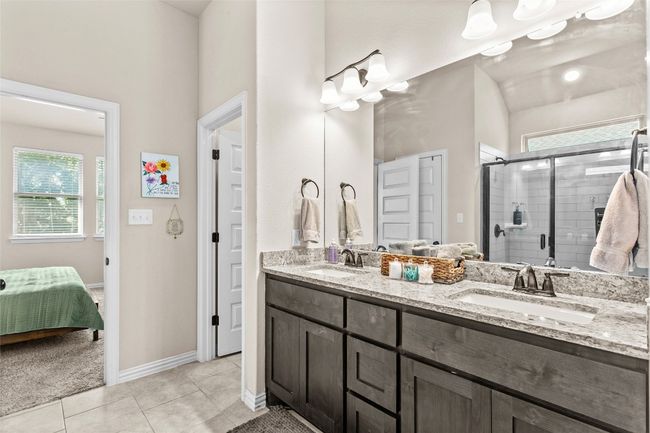 Ensuite bathroom featuring healthy amount of natural light, double vanity, a stall shower, and tile patterned flooring | Image 17