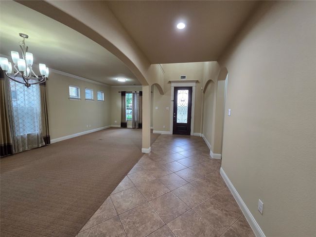 Tiled foyer featuring arched walkways, a chandelier, recessed lighting, and carpet | Image 11