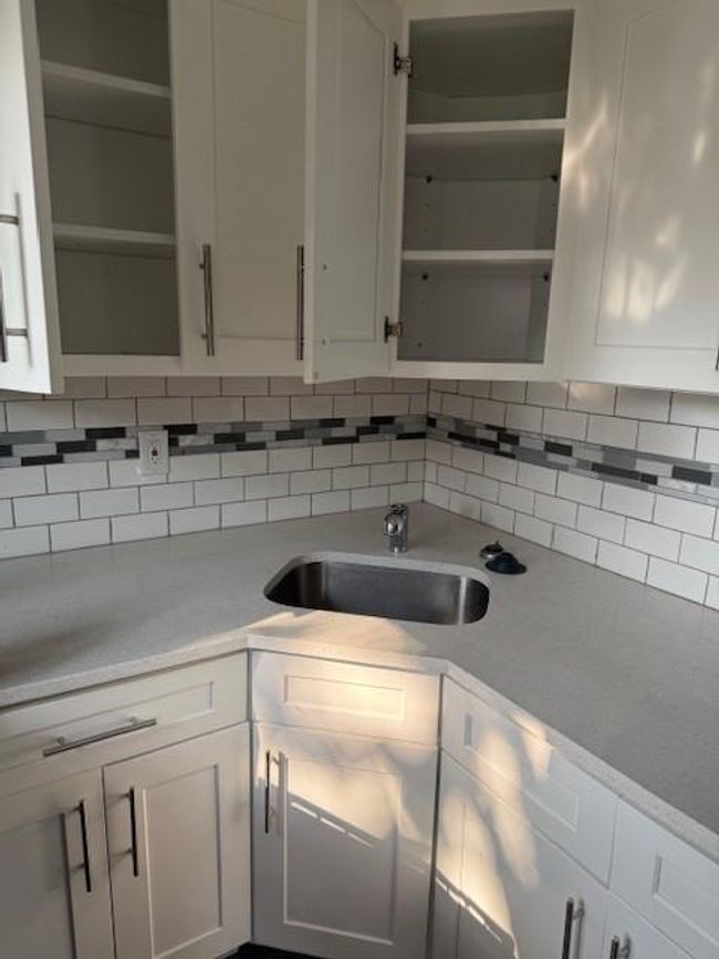 Kitchen featuring open shelves, light countertops, backsplash, and white cabinetry | Image 6