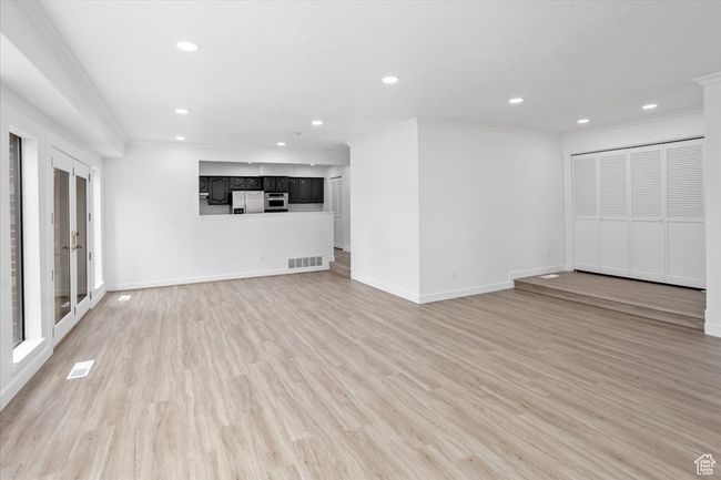 Unfurnished living room with visible vents, baseboards, ornamental molding, recessed lighting, and light wood-style floors | Image 14