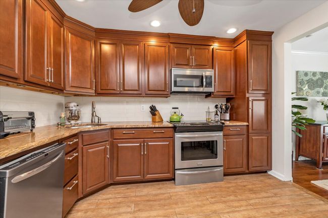 Kitchen featuring stainless steel appliances, tasteful backsplash, and light stone counters | Image 5