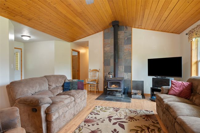 Living room featuring a wood stove, vaulted ceiling, light wood-style flooring, and wooden ceiling | Image 21