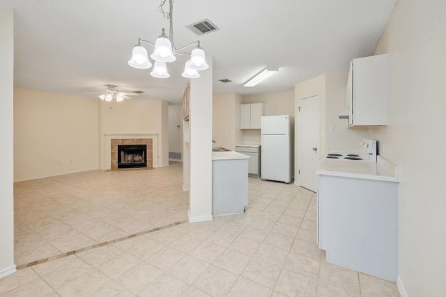 Kitchen with white appliances, ceiling fan, light countertops, a tile fireplace, and exhaust hood | Image 9