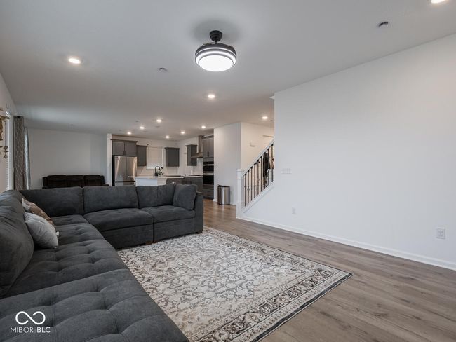 living area featuring wood finished floors, recessed lighting, baseboards, and stairs | Image 12