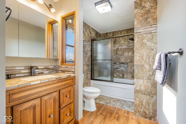 bathroom with toilet, backsplash, vanity, wood finished floors, and enclosed tub / shower combo | Image 16