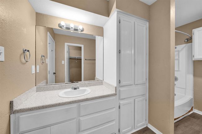Bathroom featuring baseboards, wood finished floors, vanity, shower / bathing tub combination, and a textured wall | Image 11