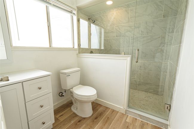 Bathroom featuring a shower stall, toilet, wood finished floors, and baseboards | Image 8