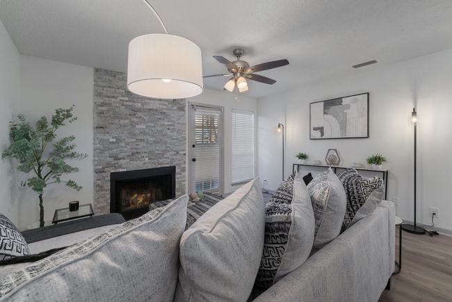 Living room with a ceiling fan, wood finished floors, a fireplace, baseboards, and visible vents | Image 12