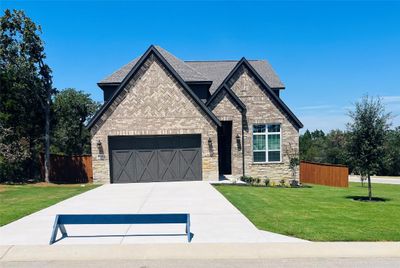 The Welch plan at The Colony is a beautiful two-story home with a long driveway, gorgeous cedar garage door, and lush front yard landscaping. | Image 1