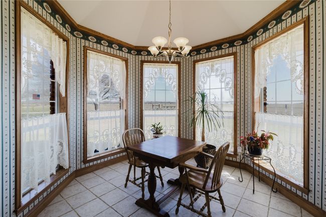 Dining space with light tile patterned flooring, vaulted ceiling, an inviting chandelier, and crown molding | Image 12