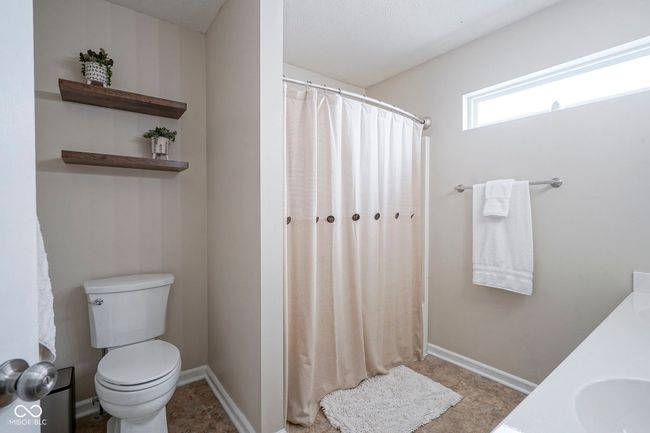 full bath with baseboards, a shower with shower curtain, toilet, and a sink | Image 22