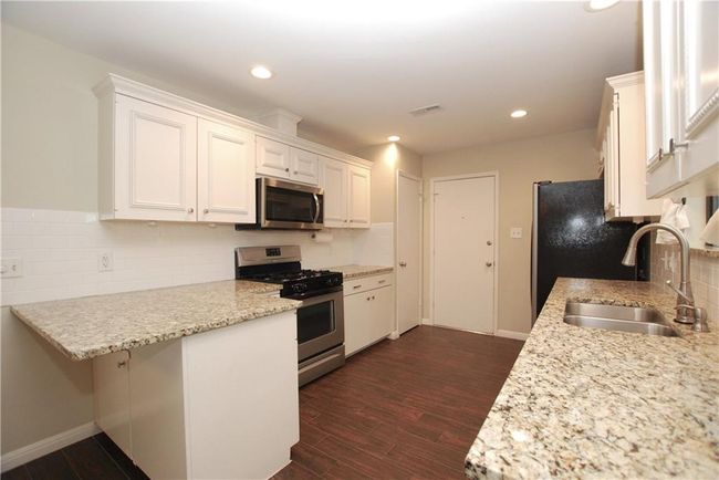 Kitchen with appliances with stainless steel finishes, white cabinetry, backsplash, dark wood-style floors, and recessed lighting | Image 7