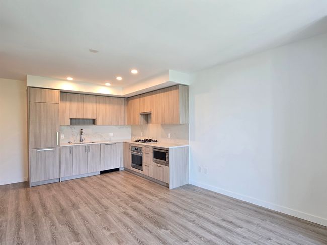 Kitchen with modern cabinets, stainless steel appliances, light countertops, light brown cabinetry, and light wood-type flooring | Image 5