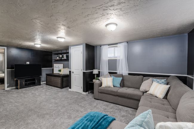 Newly carpeted living room featuring a textured ceiling and baseboards | Image 16