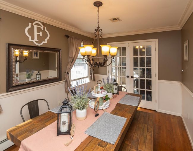 Dining room featuring an inviting chandelier, visible vents, french doors, hardwood / wood-style flooring, and baseboard heating | Image 7
