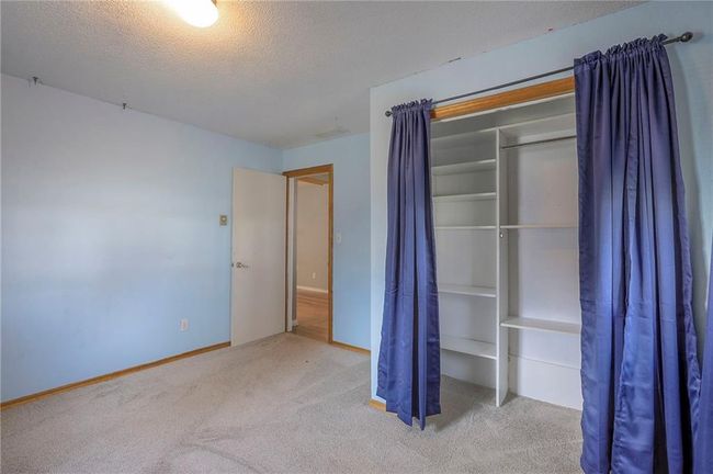 Unfurnished bedroom with carpet flooring, baseboards, a closet, and a textured ceiling | Image 34