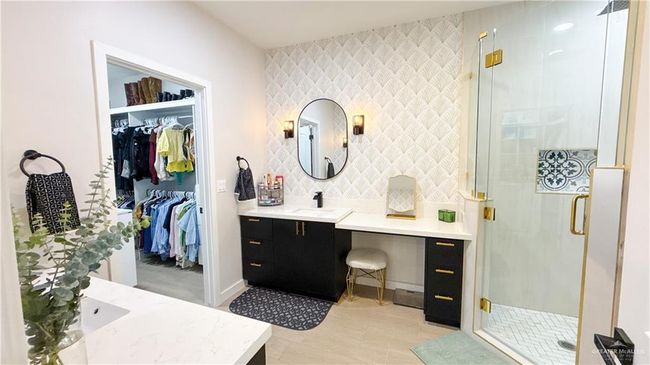 Full bathroom featuring vanity, a stall shower, a spacious closet, and an accent wall | Image 11